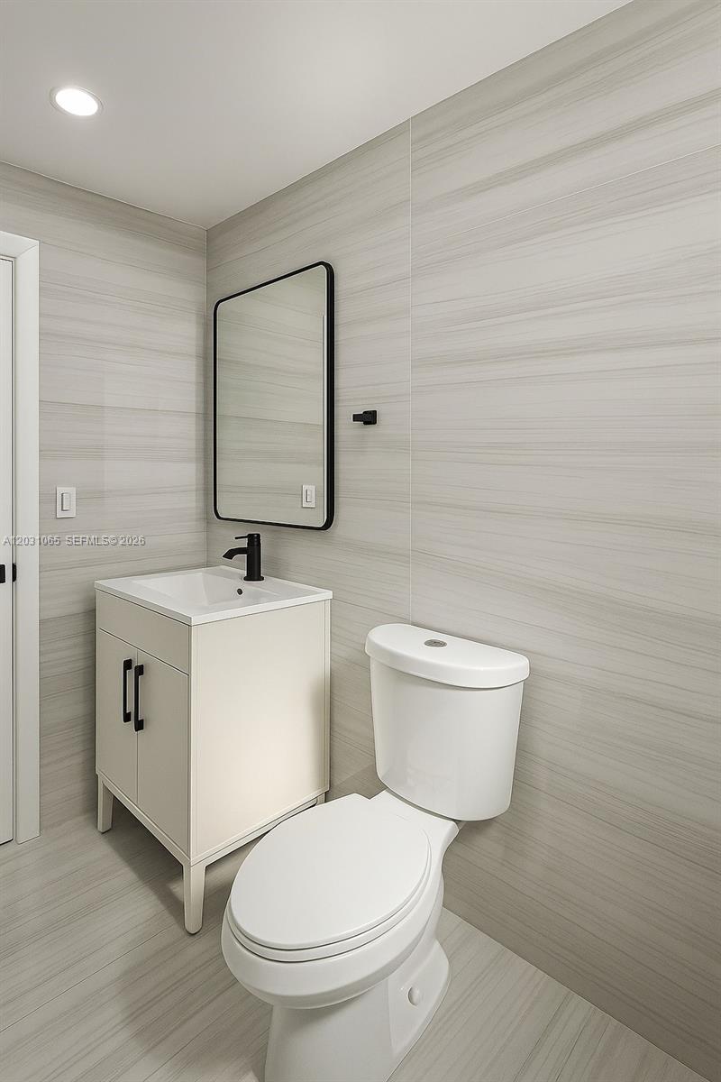 A modern bathroom features a white vanity, black faucet, rectangular mirror, and light-toned wall tiles — 5740 Mayo St # 4, Hollywood FL 33023, HOLLYWOOD, FL