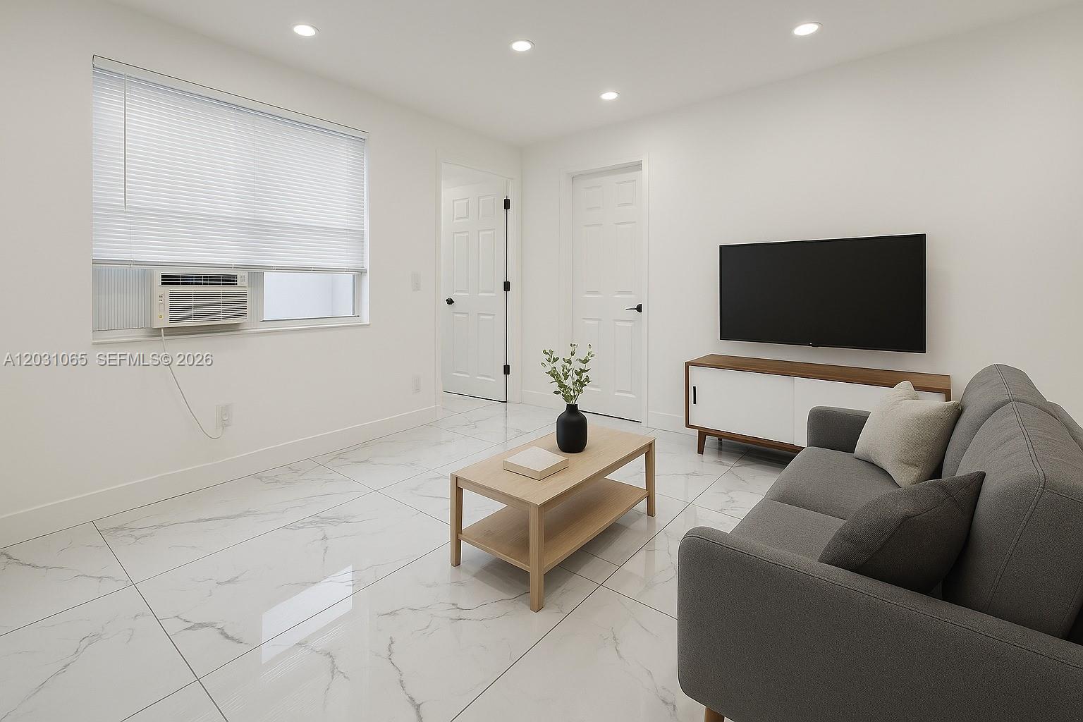 A living room features white marble flooring, a grey sofa, and a wall-mounted television — 5740 Mayo St # 4, Hollywood FL 33023, HOLLYWOOD, FL