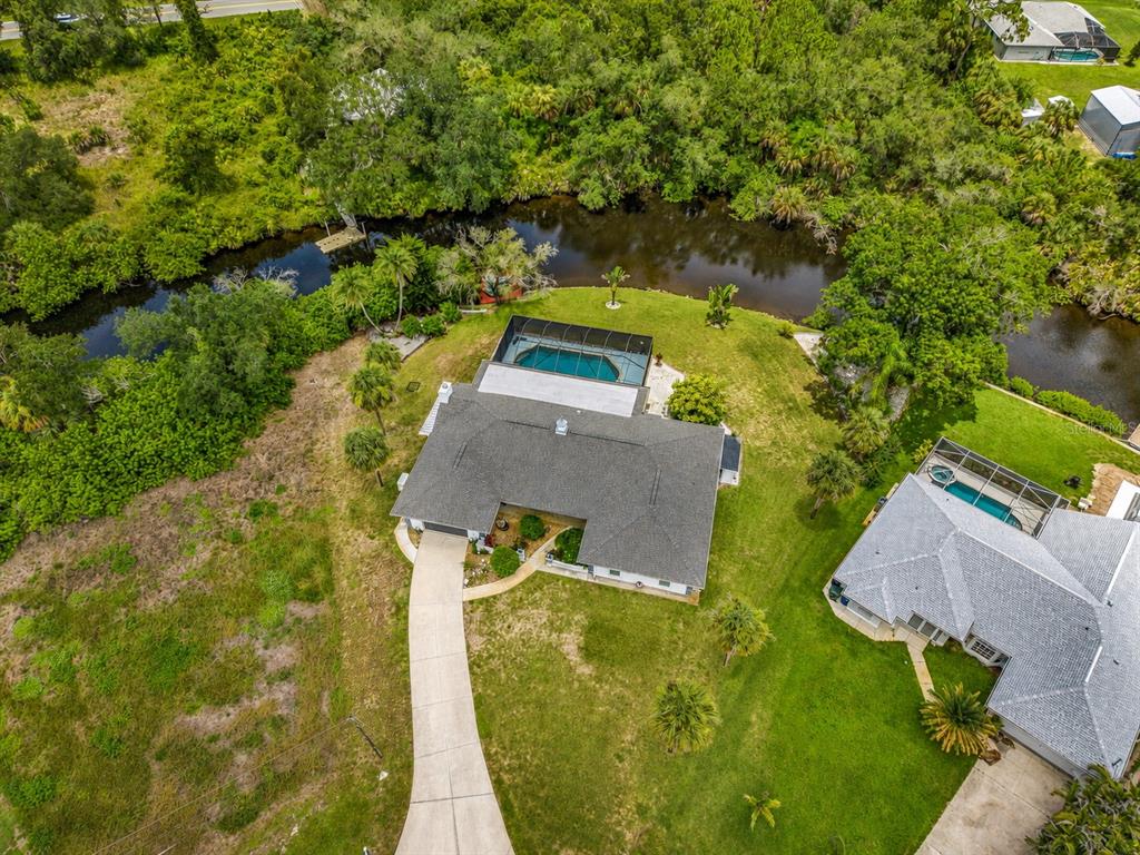 An aerial view shows a house with a screened pool, driveway, and surrounding green landscape — 108 ANTILLA ROAD, NORTH PORT, FL