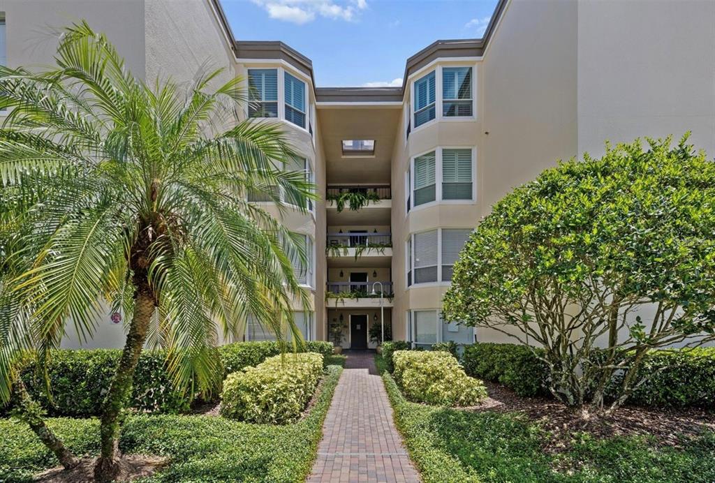 A brick walkway leads to the entrance of a multi-story apartment building with balconies — 204 QUAYSIDE CIRCLE UNIT 201, MAITLAND, FL