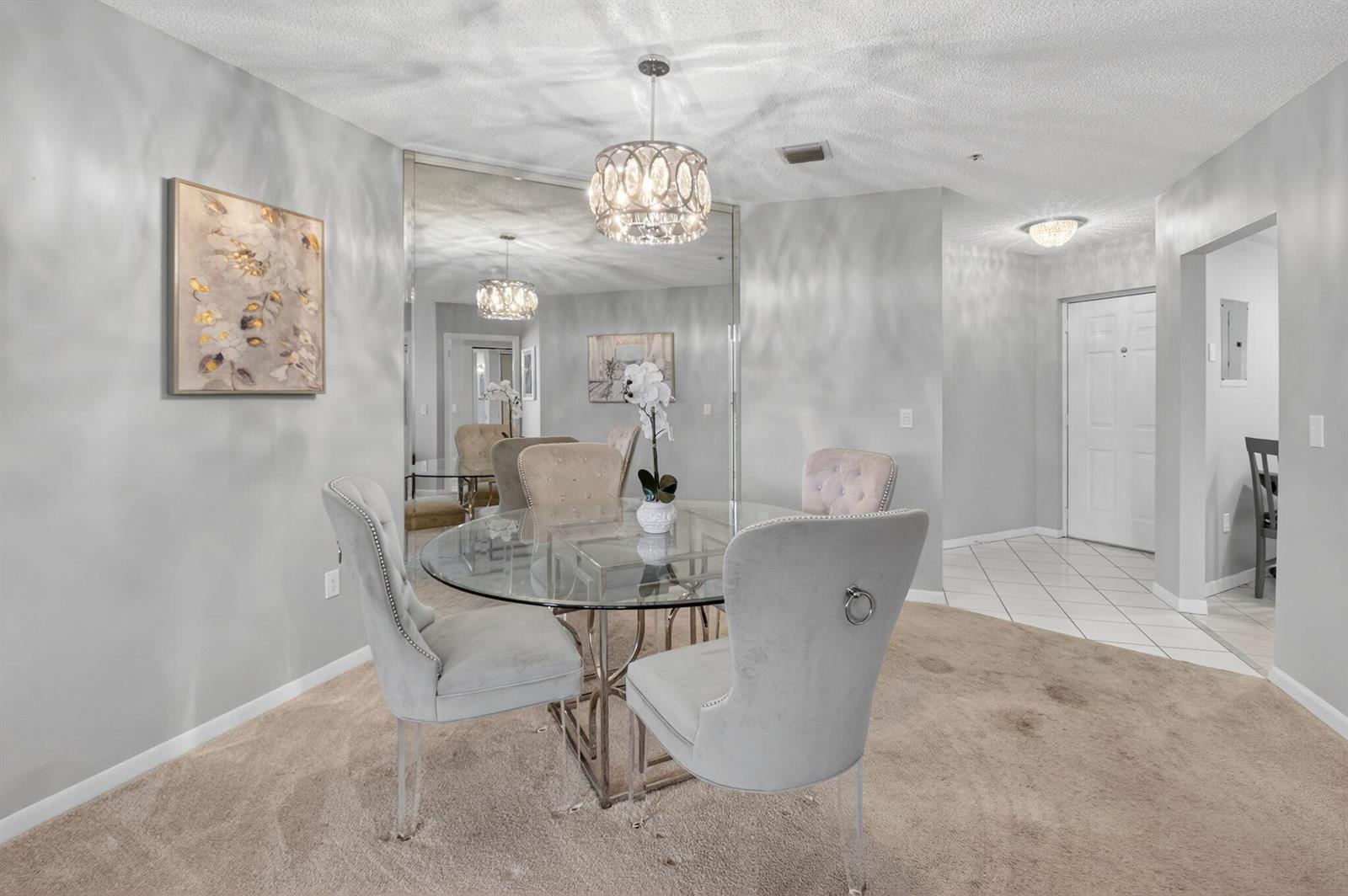 A dining area features a glass table, four upholstered chairs, and a large wall mirror — 5155 Europa Drive # M, Boynton Beach FL 33437, BOYNTON BEACH, FL