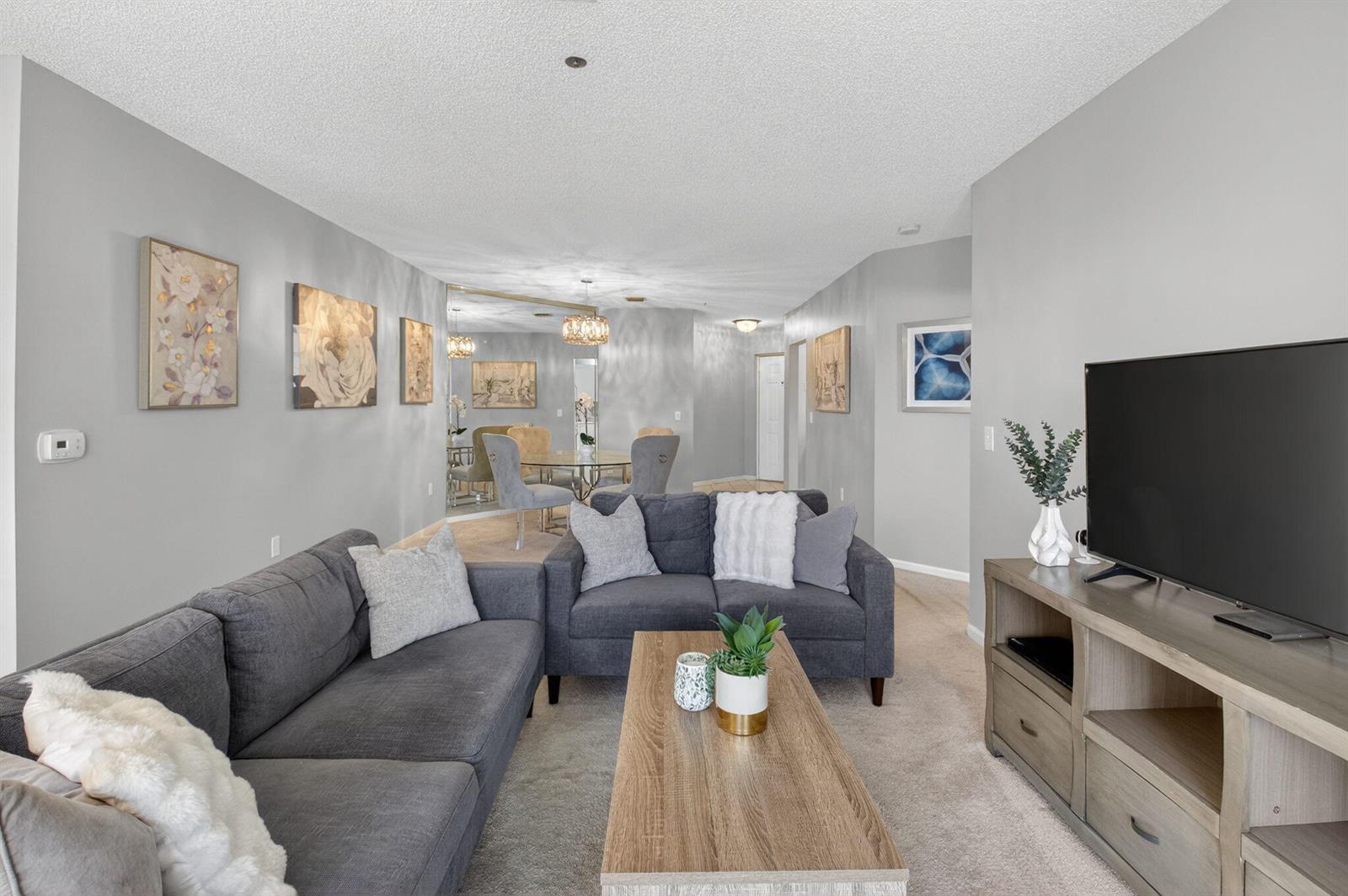 A living room features a gray sectional sofa, a wooden coffee table, and a television — 5155 Europa Drive # M, Boynton Beach FL 33437, BOYNTON BEACH, FL