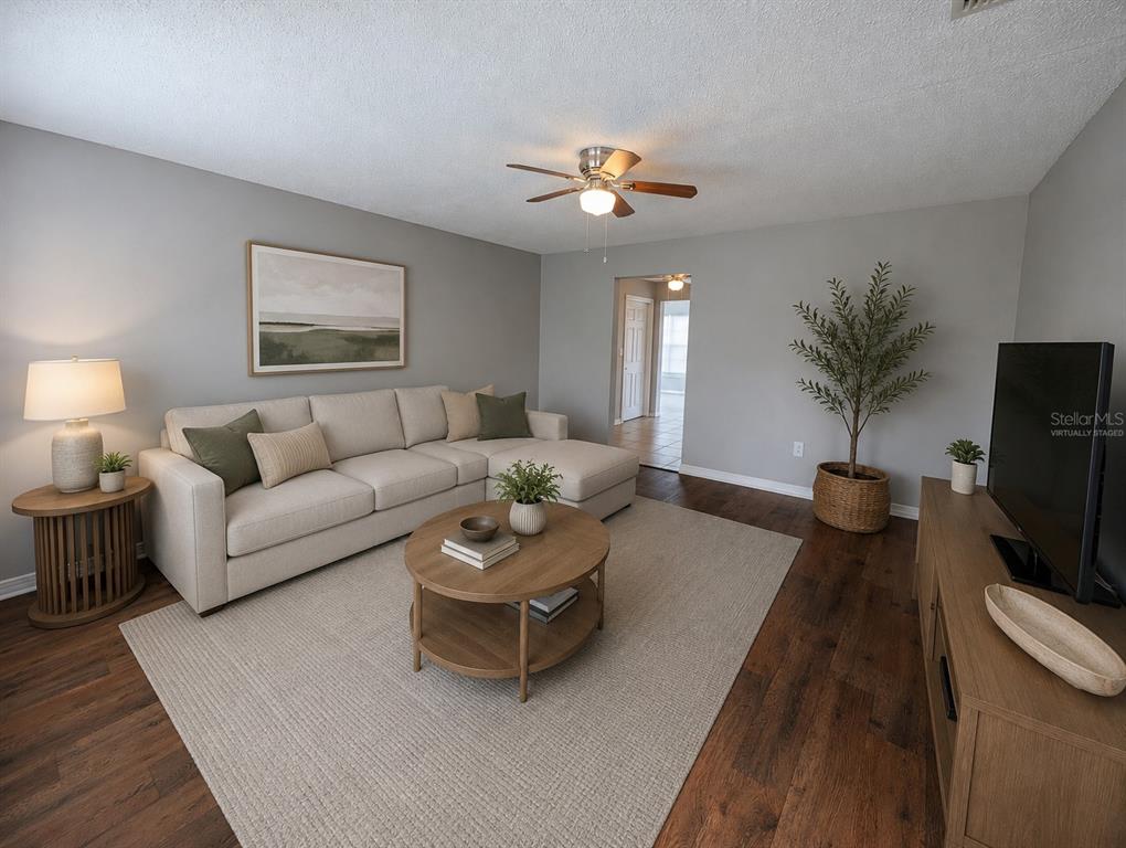 A living room features a beige sectional sofa, a round wooden coffee table, and dark flooring — 3153 LODI DRIVE, NEW PORT RICHEY, FL