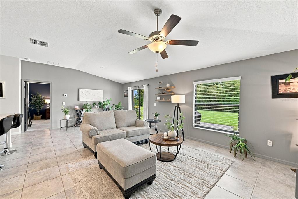 A living room with gray walls, tile flooring, a ceiling fan, and a sliding glass door — 7109 SALT RIVER AVENUE, SUN CITY CENTER, FL