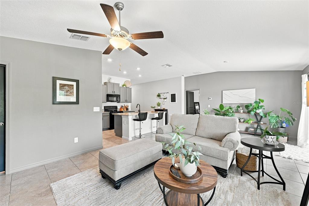 A living room with a gray sofa, ottoman, and coffee table opens to a kitchen — 7109 SALT RIVER AVENUE, SUN CITY CENTER, FL