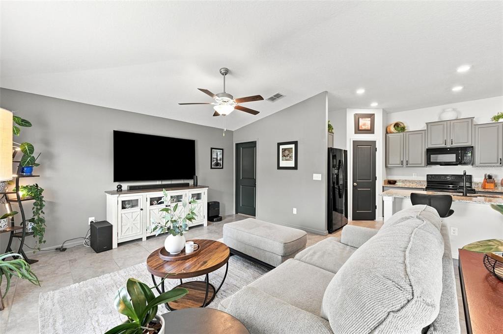 A living room features gray walls, a white media console, and an open kitchen area — 7109 SALT RIVER AVENUE, SUN CITY CENTER, FL