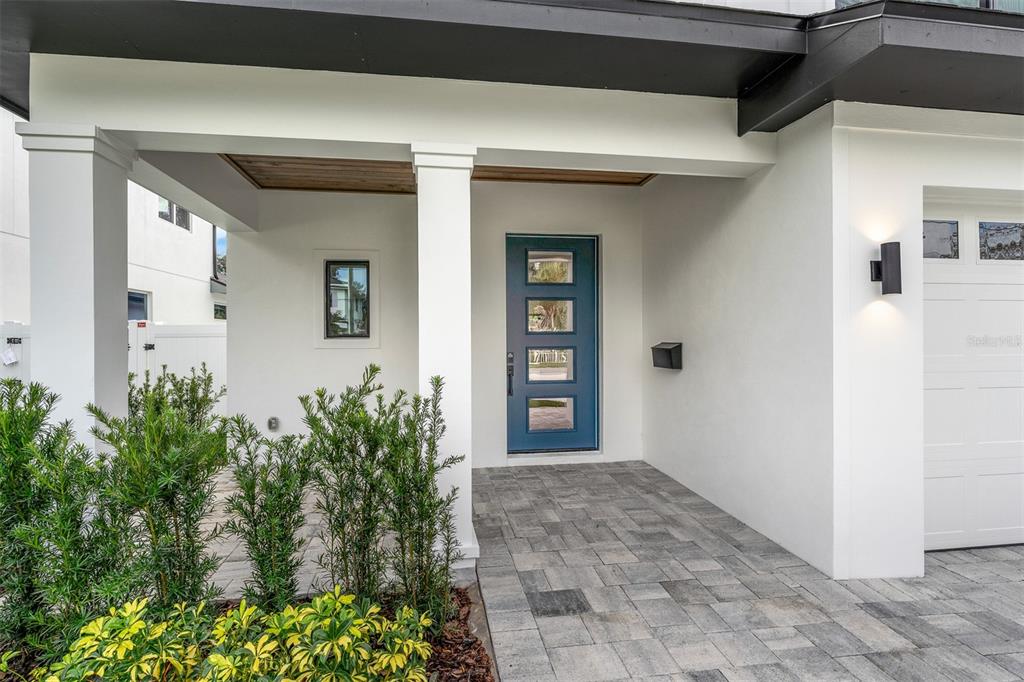 A modern home exterior features a blue front door, white walls, and a paved porch — 1546 MILLER AVENUE, WINTER PARK, FL