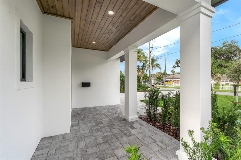 A covered front porch features white columns, a wood-plank ceiling, and gray paver flooring — 1546 MILLER AVENUE, WINTER PARK, FL