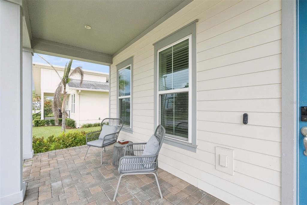 A covered front porch features light-colored siding, two gray chairs, and a paved floor — 13126 GRANGER AVENUE, ORLANDO, FL