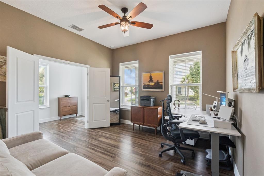 A home office with wood-look flooring, a desk, a ceiling fan, and a doorway — 13126 GRANGER AVENUE, ORLANDO, FL