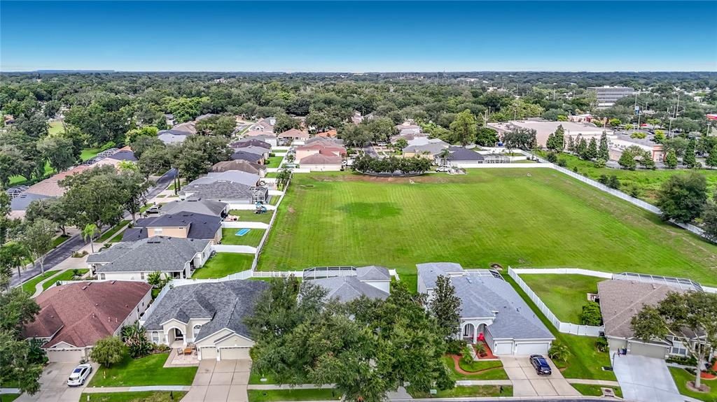 An aerial view shows a suburban neighborhood with houses bordering a large, open green field — 220 RONJA LANE, VALRICO, FL