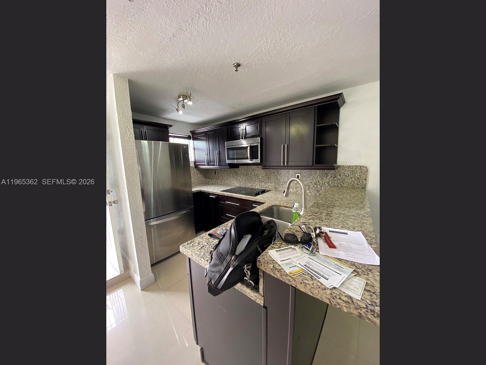 A kitchen features dark wood cabinets, granite countertops, stainless steel appliances, and tile flooring — 8031 NW 8th St # 17, Miami FL 33126, MIAMI, FL