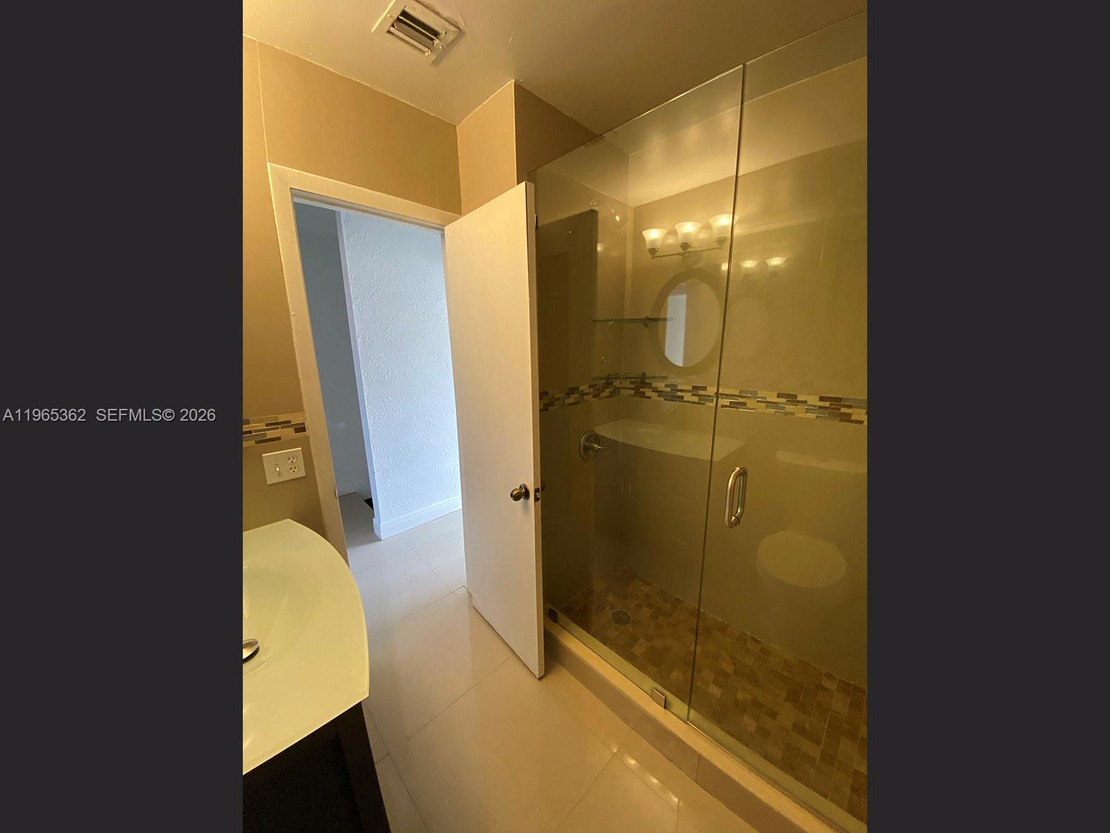 A bathroom features a glass-enclosed shower with tiled accents and a white vanity — 8031 NW 8th St # 17, Miami FL 33126, MIAMI, FL