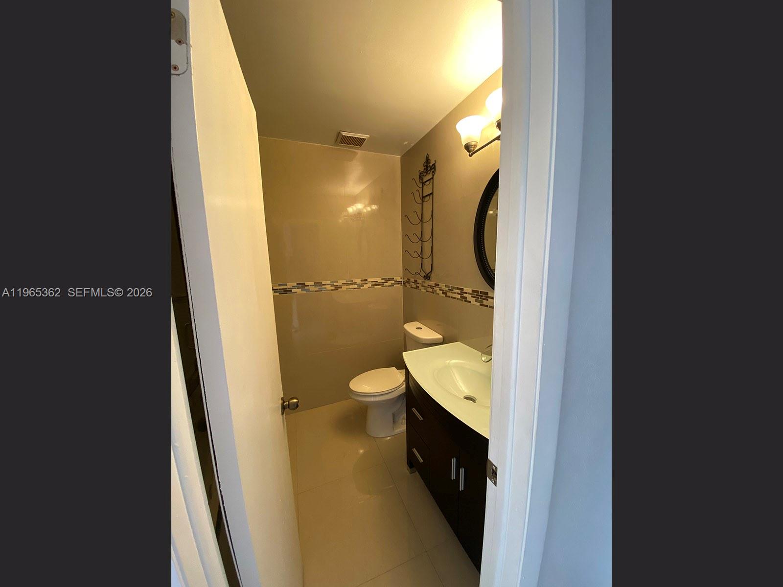 A small bathroom features a dark wood vanity, a toilet, and beige wall tiles — 8031 NW 8th St # 17, Miami FL 33126, MIAMI, FL