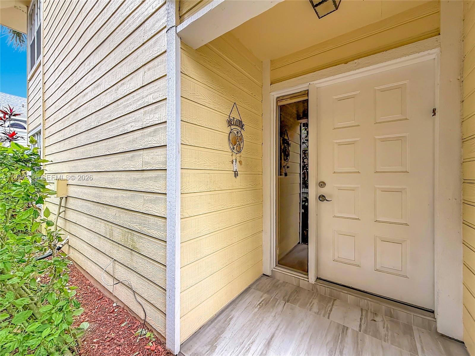 A yellow-sided house exterior features a front door with a side window and tiled porch — 5043 Pointe Emerald Ln, Boca Raton FL 33486, BOCA RATON, FL