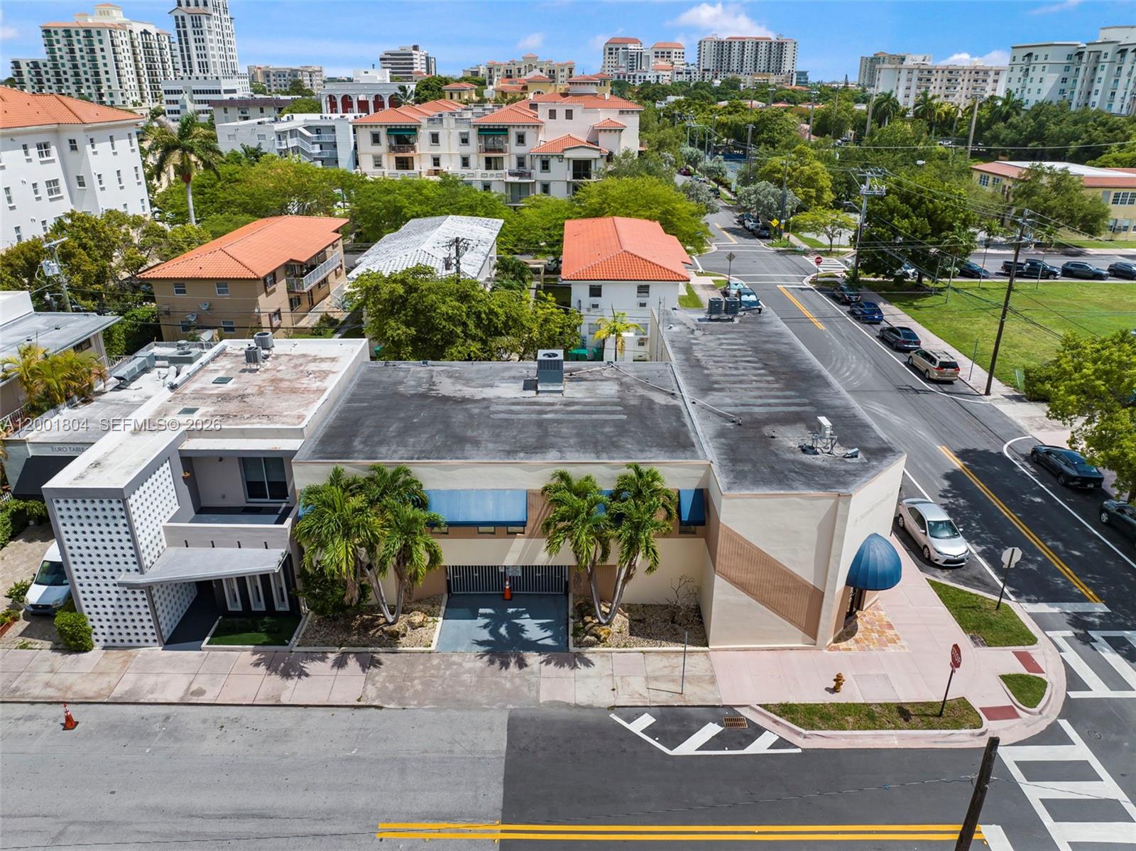 An aerial view shows a commercial building with a flat roof and palm trees — 101 Madeira Ave, Coral Gables FL 33134, CORAL GABLES, FL