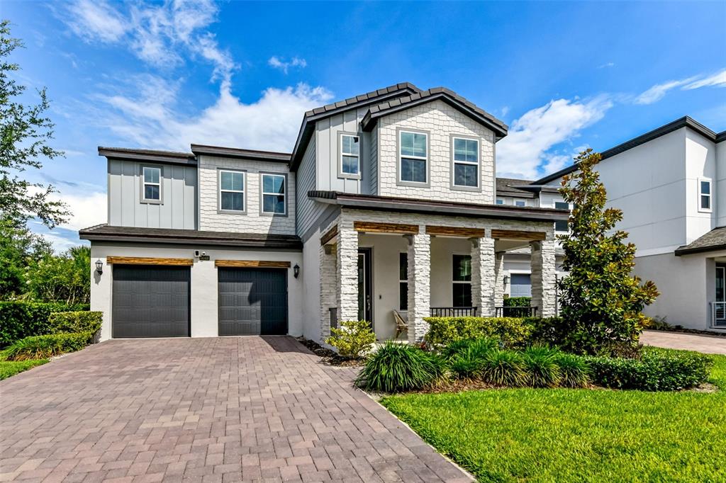 A two-story house features a stone facade, a covered porch, and a two-car garage — 6048 BIMINI TWIST LOOP, ORLANDO, FL