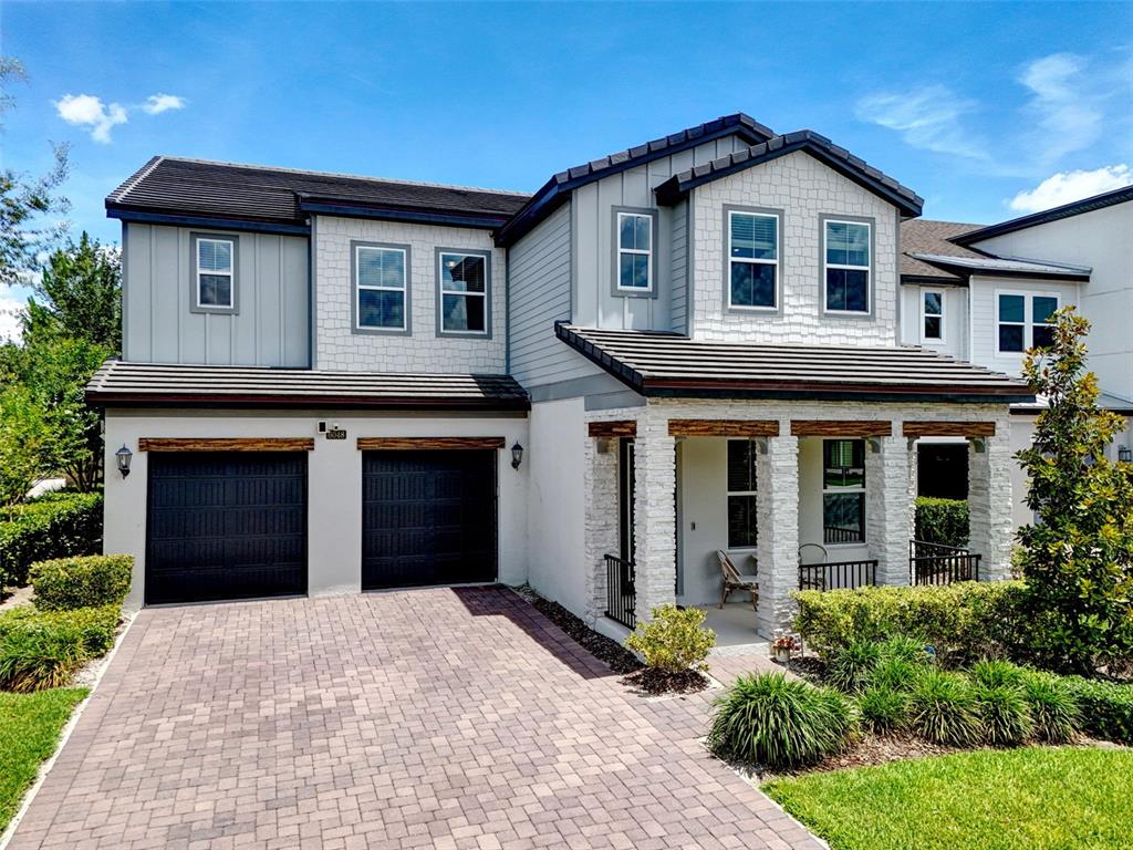 A two-story house with a paved driveway, two garage doors, and a stone-accented front porch — 6048 BIMINI TWIST LOOP, ORLANDO, FL