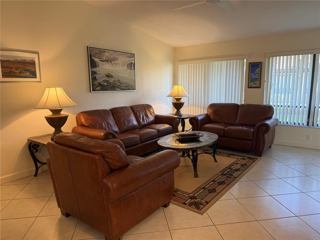 A living room features brown leather furniture, a round coffee table, and tile flooring — 3637 YELLOW PINE COURT UNIT 146, SARASOTA, FL