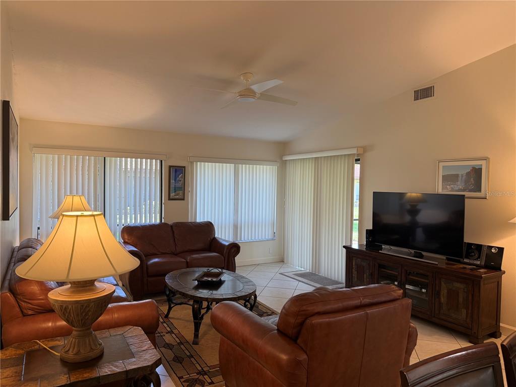 A living room features leather furniture, a television on a wooden console, and tile flooring — 3637 YELLOW PINE COURT UNIT 146, SARASOTA, FL