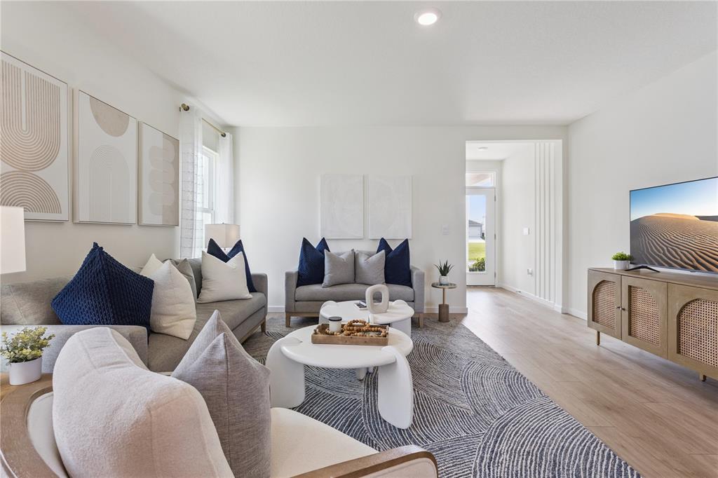 A living room features gray sofas, a patterned area rug, and a wood media console — 5199 NICKERBEAN STREET, APOPKA, FL