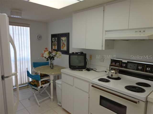 A kitchen with white cabinets, a white stove, and a small dining table with two chairs — 5278 WEDGEWOOD LANE UNIT 48, SARASOTA, FL