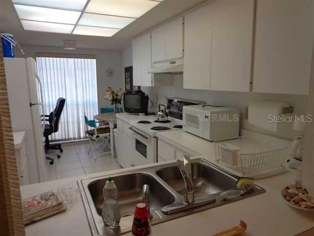 A kitchen with white cabinets, a double sink, and a dining area near a window — 5278 WEDGEWOOD LANE UNIT 48, SARASOTA, FL