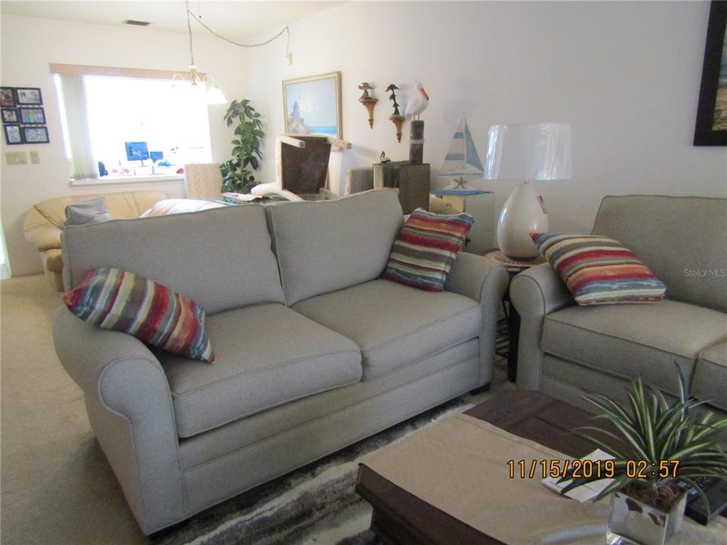 A living room features a light-colored sofa and armchair with striped accent pillows — 5278 WEDGEWOOD LANE UNIT 48, SARASOTA, FL