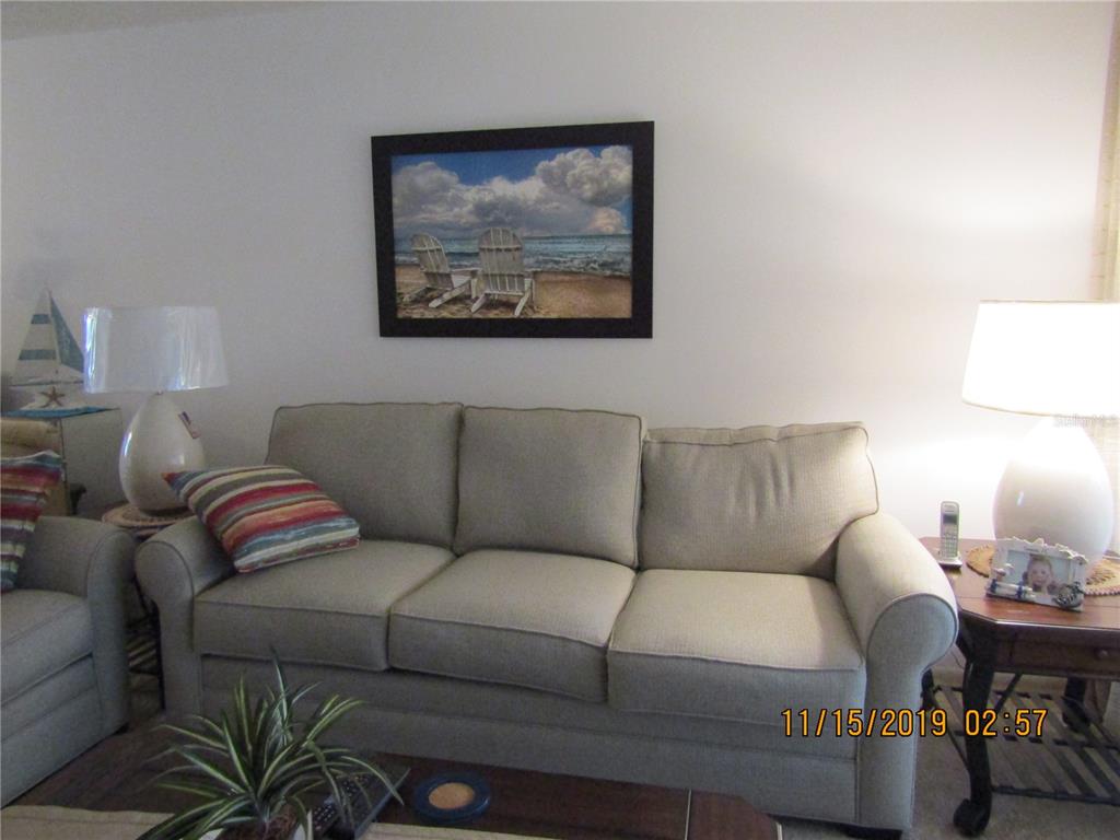 A living room features a beige sofa, two lamps, and a beach-themed wall picture — 5278 WEDGEWOOD LANE UNIT 48, SARASOTA, FL