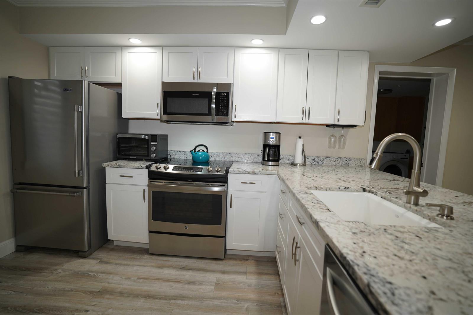 A kitchen with white cabinets, stainless steel appliances, and speckled granite countertops — 2101 Marina Isle Way # 104, Jupiter FL 33477, JUPITER, FL