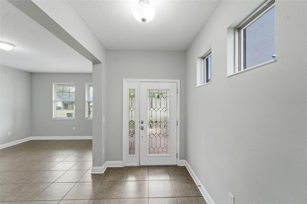An entryway with tile flooring, a white front door with glass panels, and light-colored walls — 175 ANCONA AVENUE, DEBARY, FL