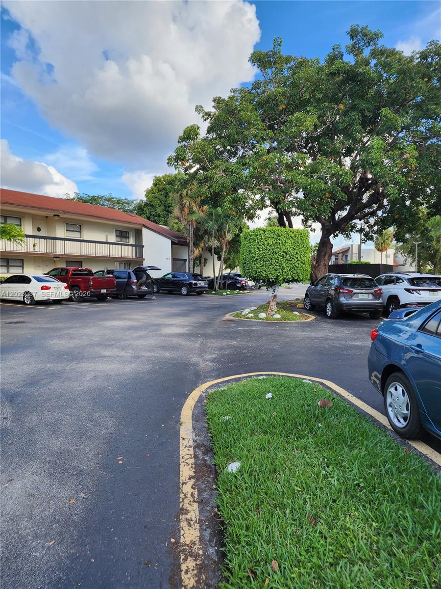 An outdoor parking lot features several parked cars in front of a two-story apartment building — 461 NW 107 Ave # 102, Miami FL 33172, MIAMI, FL
