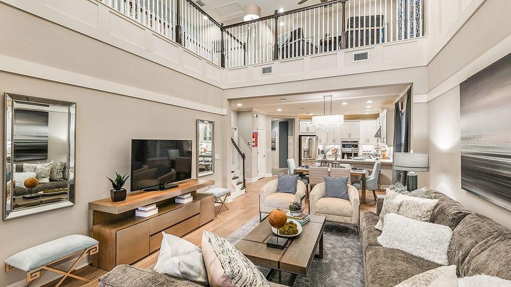 A living room with a two-story ceiling, hardwood floors, and an open-concept kitchen — 7012 FOXBORO WAY, NOKOMIS, FL