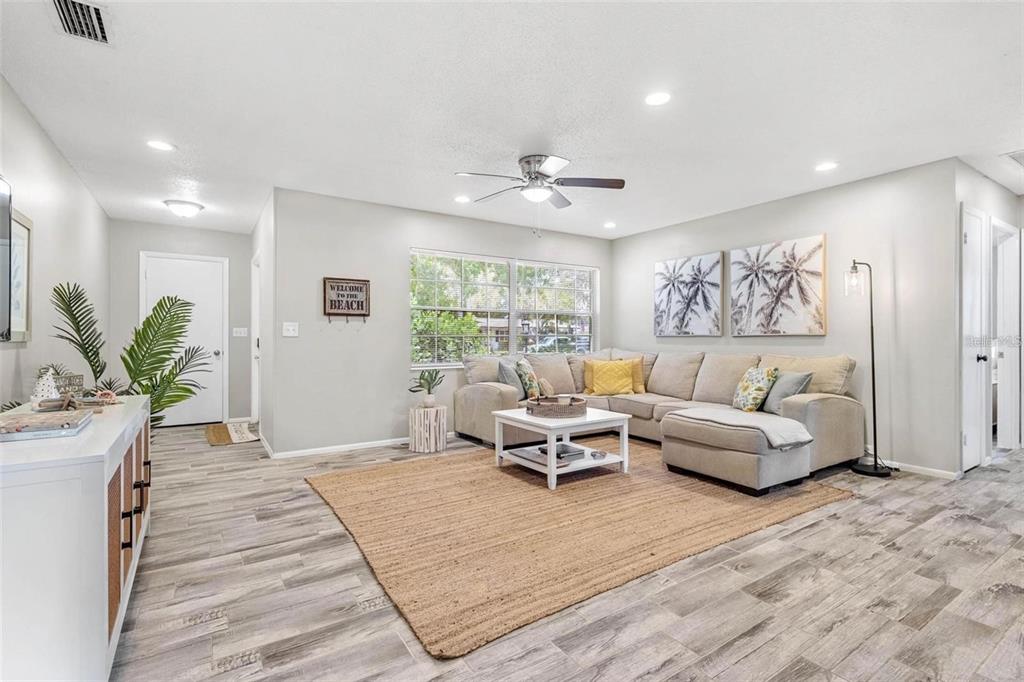 A living room features a beige sectional sofa, a jute rug, and light wood-look flooring — 4904 19TH AVENUE W, BRADENTON, FL