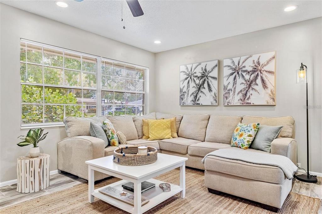 A living room features a beige sectional sofa, a white coffee table, and palm tree artwork — 4904 19TH AVENUE W, BRADENTON, FL