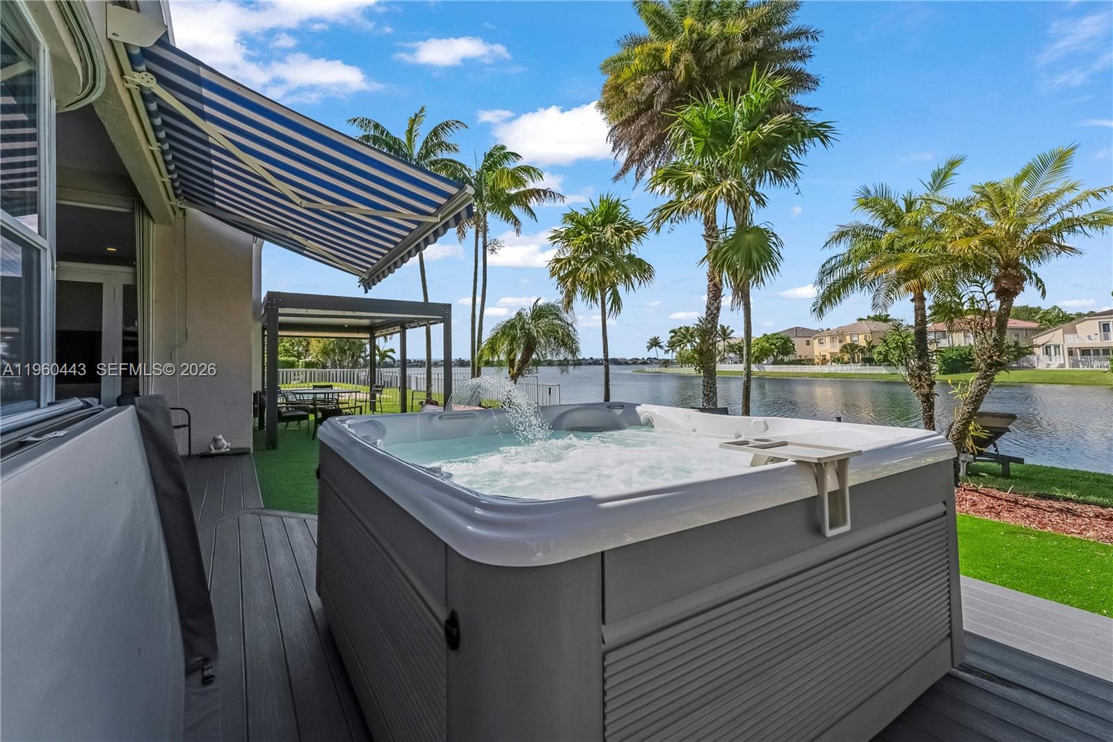 A hot tub sits on a deck overlooking a lake with palm trees and houses — 5046 SW 162nd Ave, Miramar FL 33027, MIRAMAR, FL