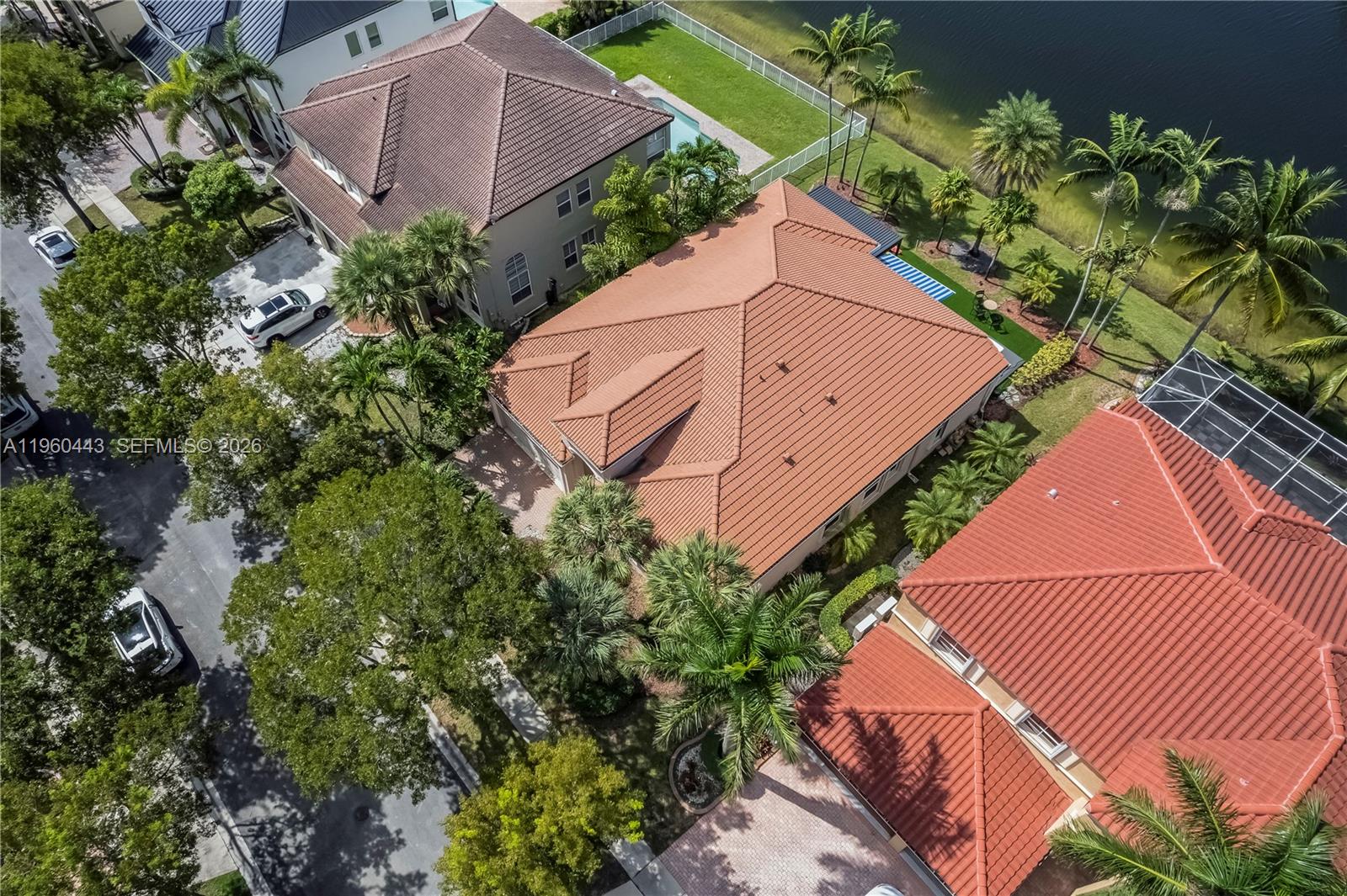 An aerial view shows three houses with red tile roofs and palm trees near water — 5046 SW 162nd Ave, Miramar FL 33027, MIRAMAR, FL