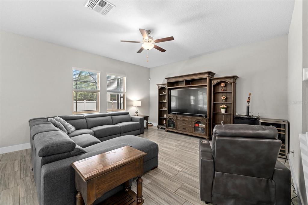 A living room features a large gray sectional sofa, a dark wood entertainment center, and tile flooring — 7612 S JUANITA STREET, TAMPA, FL