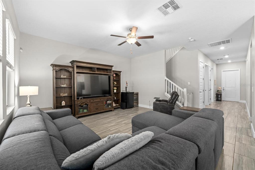 A living room features a large gray sectional sofa, a wooden entertainment center, and tile flooring — 7612 S JUANITA STREET, TAMPA, FL