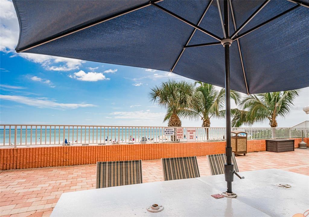 A patio with a table and umbrella overlooks a beach and ocean — 18400 GULF BOULEVARD UNIT 2405, INDIAN SHORES, FL