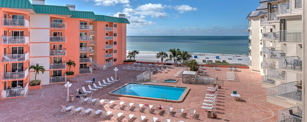 An elevated view of a resort pool area between two multi-story buildings facing the ocean — 18400 GULF BOULEVARD UNIT 2405, INDIAN SHORES, FL