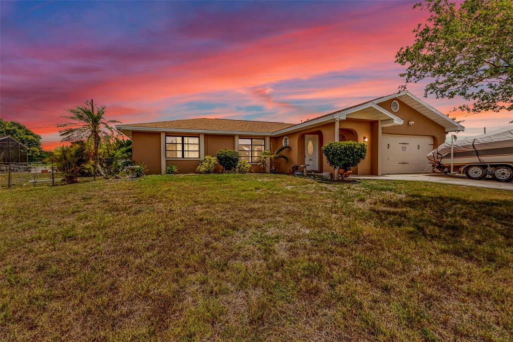 A single-story house with a brown exterior, a two-car garage, and a boat parked outside — 19519 MIDWAY BOULEVARD, PORT CHARLOTTE, FL