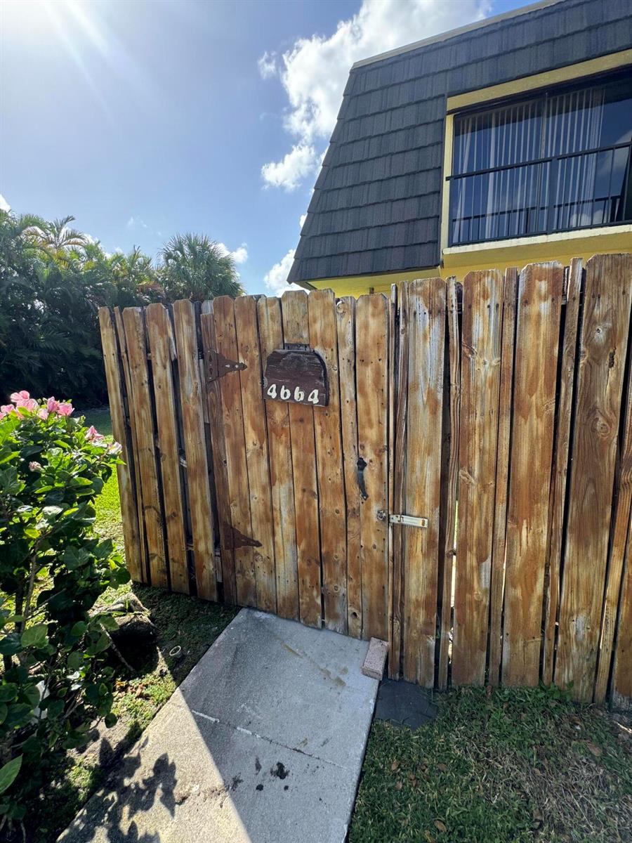 A wooden fence with a house number sign stands in front of a building exterior — 4664 Cherry Road, West Palm Beach FL 33417, WEST PALM BEACH, FL