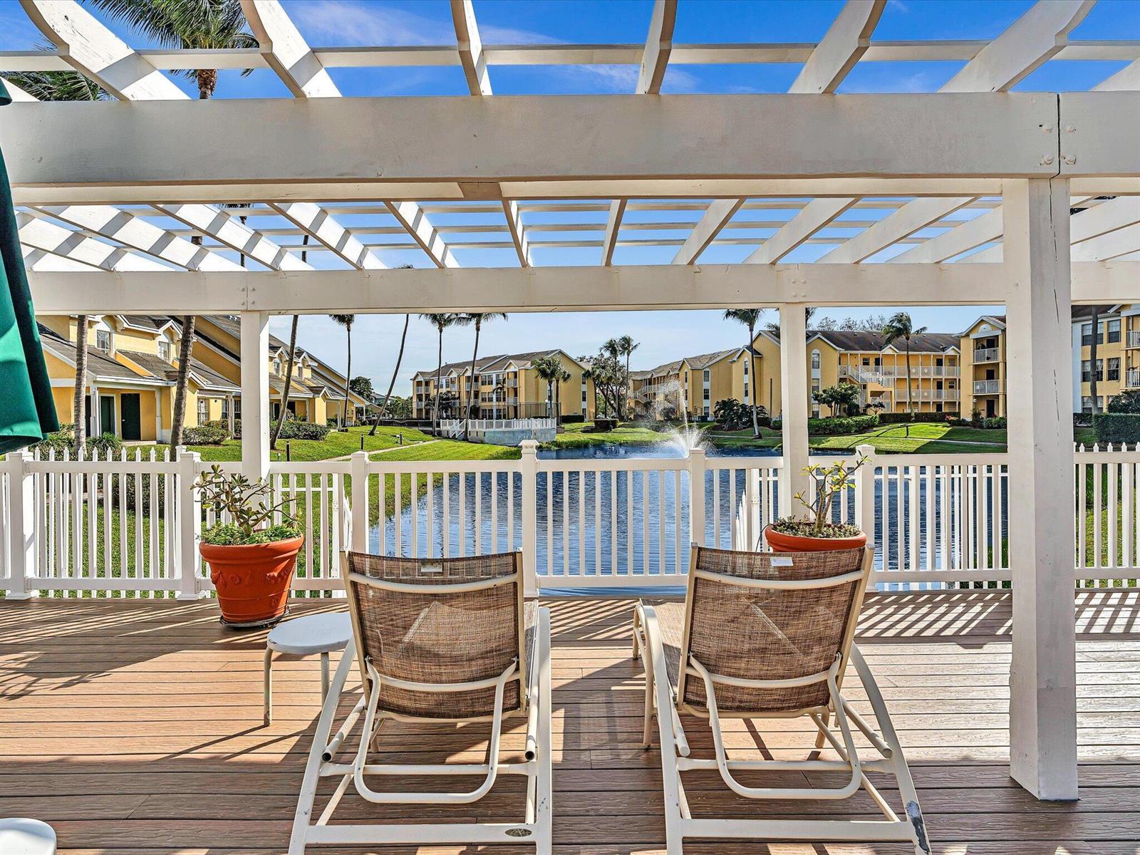 Two lounge chairs sit on a wooden deck under a pergola overlooking a pond — 6284 La Costa Drive # K, Boca Raton FL 33433, BOCA RATON, FL