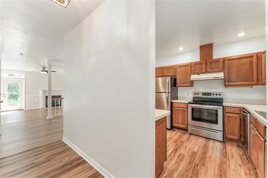 A kitchen with wood cabinets and stainless steel appliances sits beside a living area — 831 NW 42ND TERRACE, GAINESVILLE, FL
