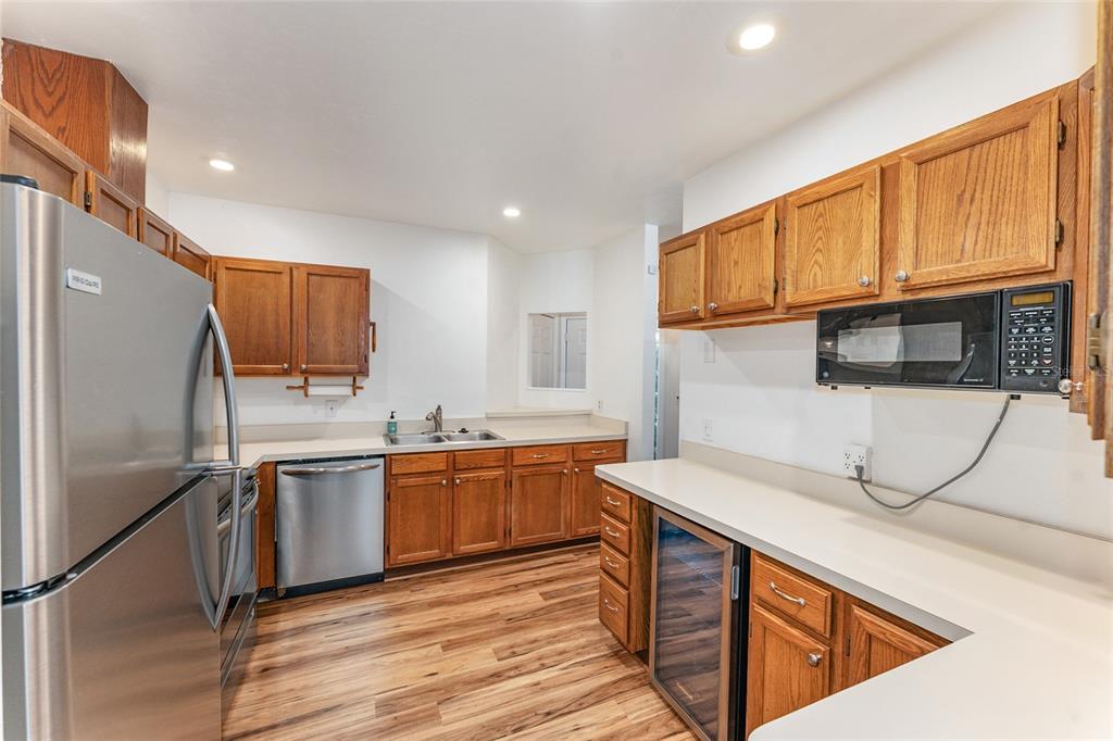 A kitchen features wood cabinets, stainless steel appliances, a wine cooler, and light-colored countertops — 831 NW 42ND TERRACE, GAINESVILLE, FL