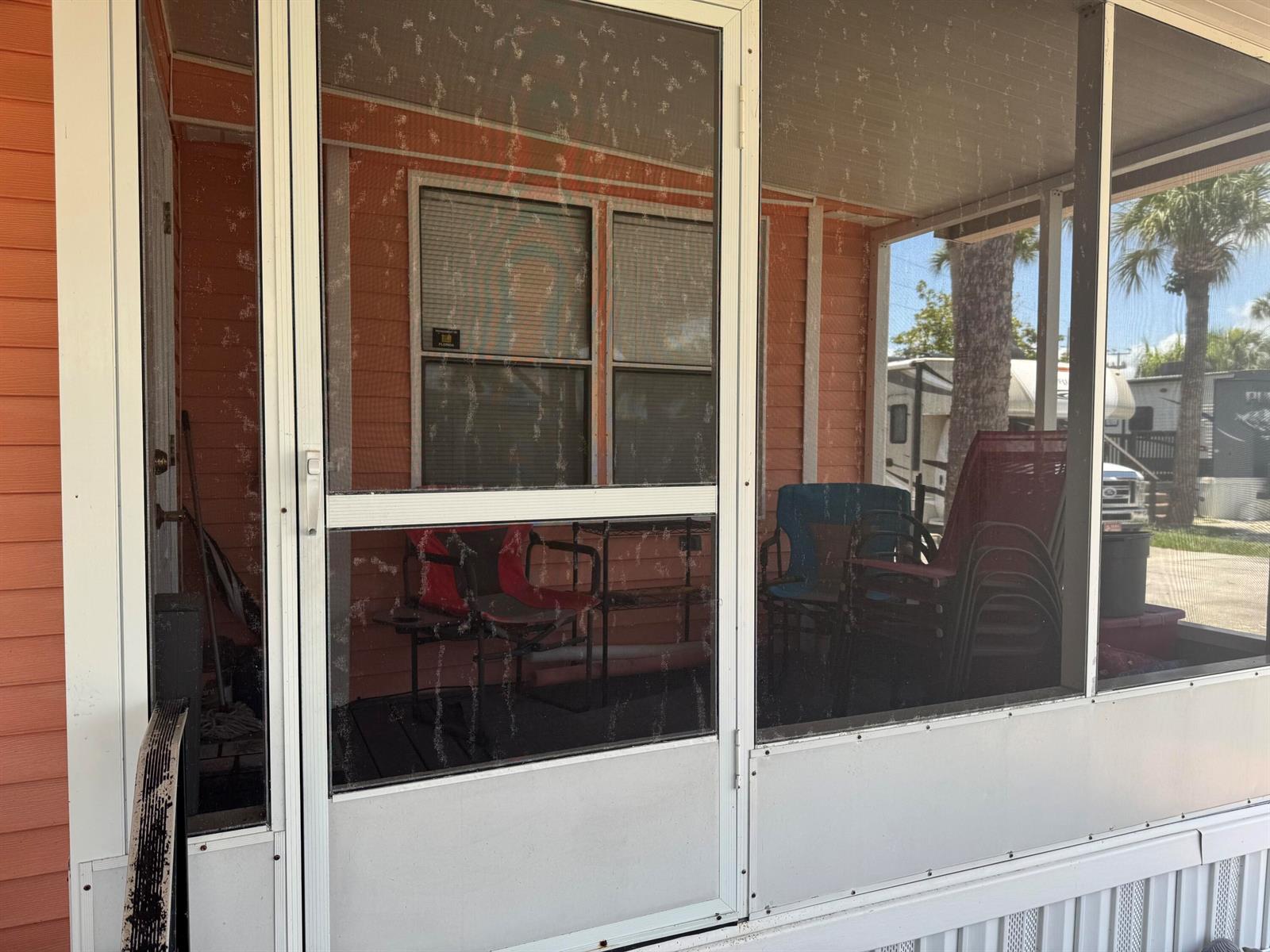 A screened-in porch features orange siding, a white door, and several outdoor chairs — 6658 SE 56th Lane, Okeechobee FL 34974, OKEECHOBEE, FL
