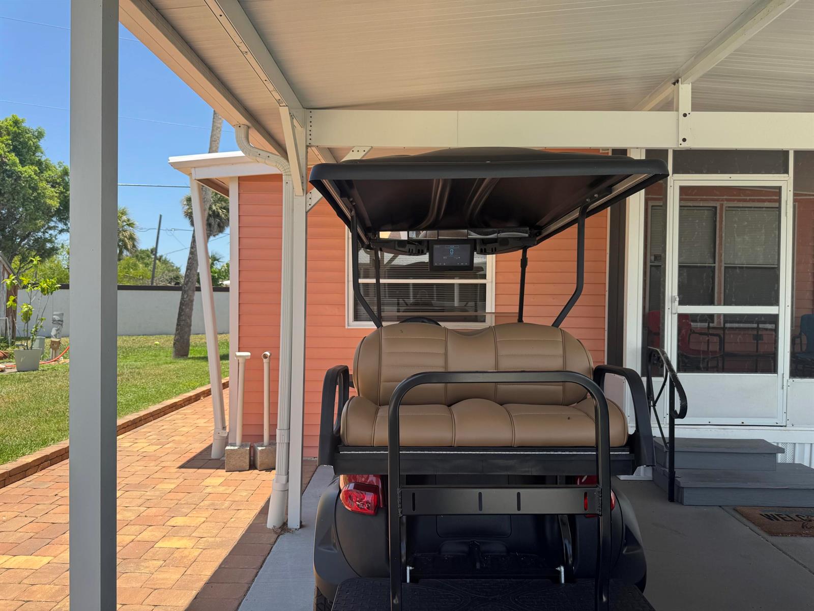 A golf cart is parked under a covered carport next to a peach-colored house — 6658 SE 56th Lane, Okeechobee FL 34974, OKEECHOBEE, FL