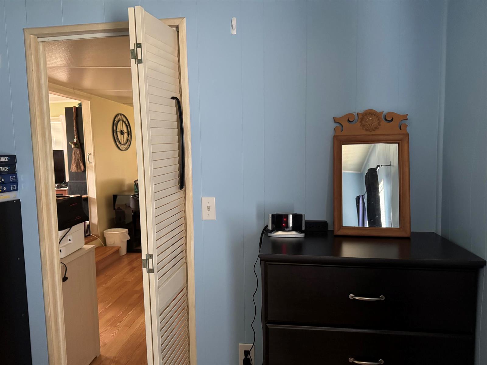 A blue-walled room features a dark dresser with a mirror and a louvered door — 6658 SE 56th Lane, Okeechobee FL 34974, OKEECHOBEE, FL