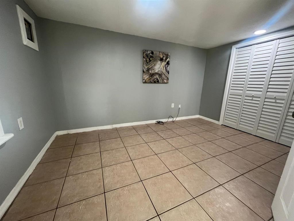 A room with gray walls, tiled flooring, and white louvered closet doors — 1400 DAKOTA AVENUE, ST CLOUD, FL